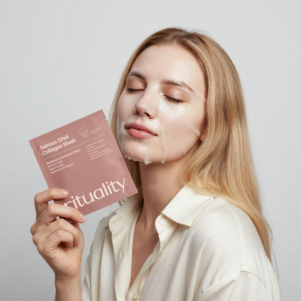 Woman wearing the Salmon DNA Collagen Mask while holding the Rituality mask packaging in soft natural light