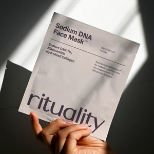 Hand holding Rituality Salmon DNA Collagen Mask package in soft sunlight with clean minimal aesthetic