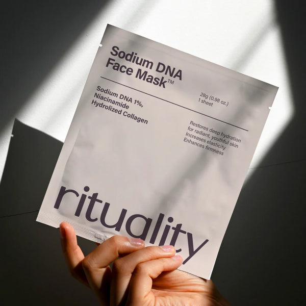 Hand holding Rituality Salmon DNA Collagen Mask package in soft sunlight with clean minimal aesthetic